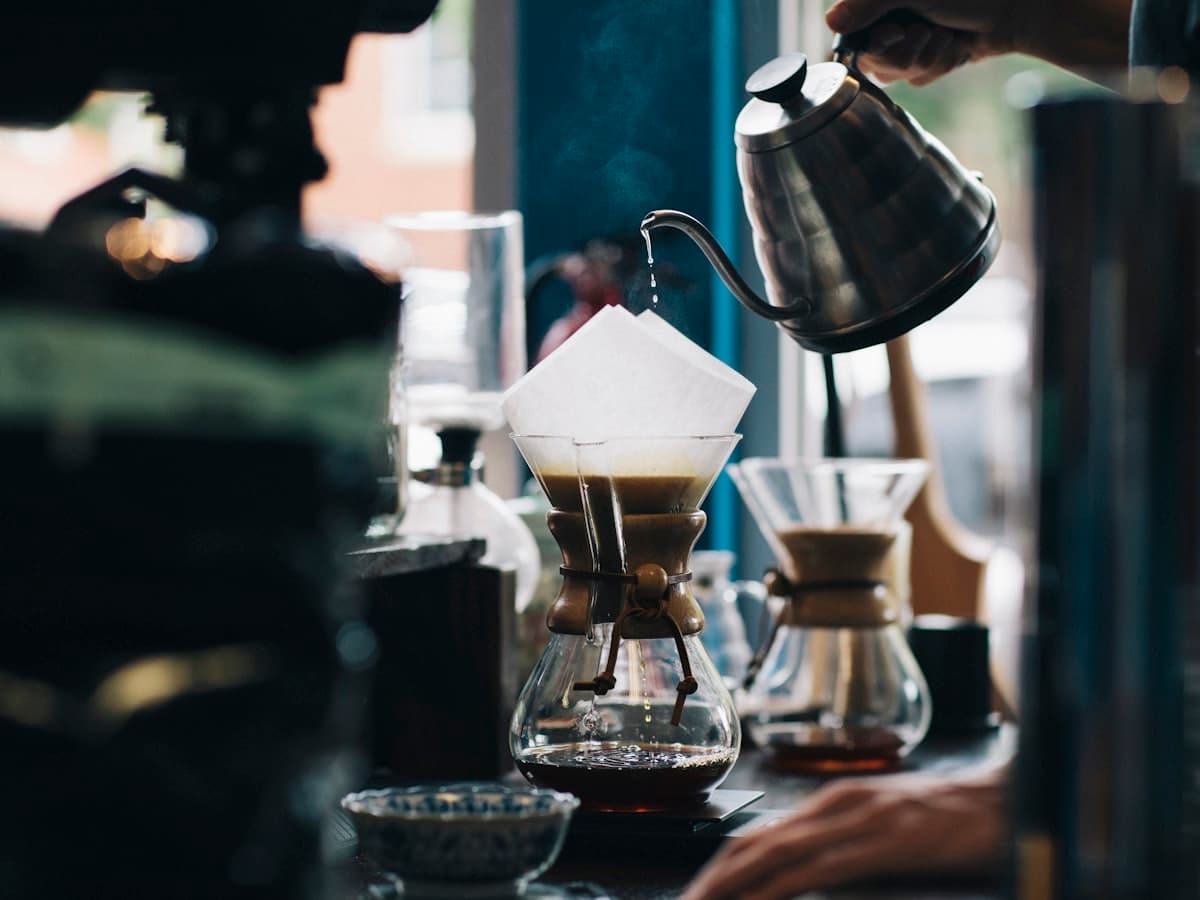 Hand pouring water over a specialty pour-over coffee at a café counter