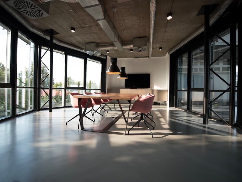 A spacious modern boardroom with a long wood table and glass walls